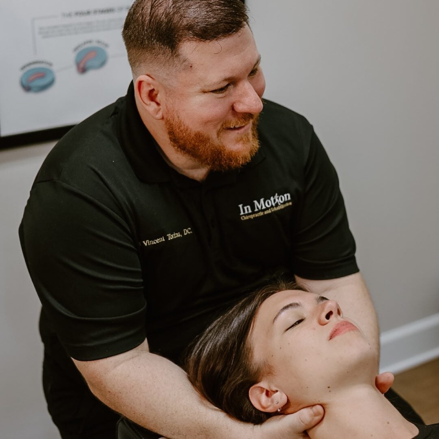 Dr. Torina cradling and treating a patient's neck at In Motion in Oviedo, FL